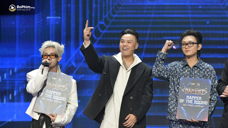 Robber đứng cùng các rapper nhận giải thưởng "Rapper of the Round", tay giơ cao thể hiện sự tự tin tại sân khấu Rap Việt.