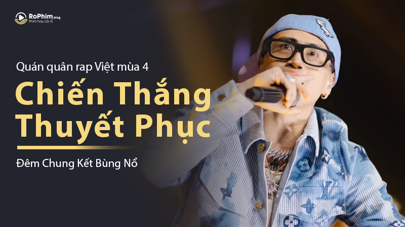 Robber giơ micro đầy tự tin tại đêm chung kết Rap Việt mùa 4, thông điệp “Chiến Thắng Thuyết Phục” nổi bật bên cạnh.